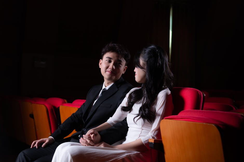 映画館でカップルが手を繋ぎロマンチックなひとときを過ごす場面