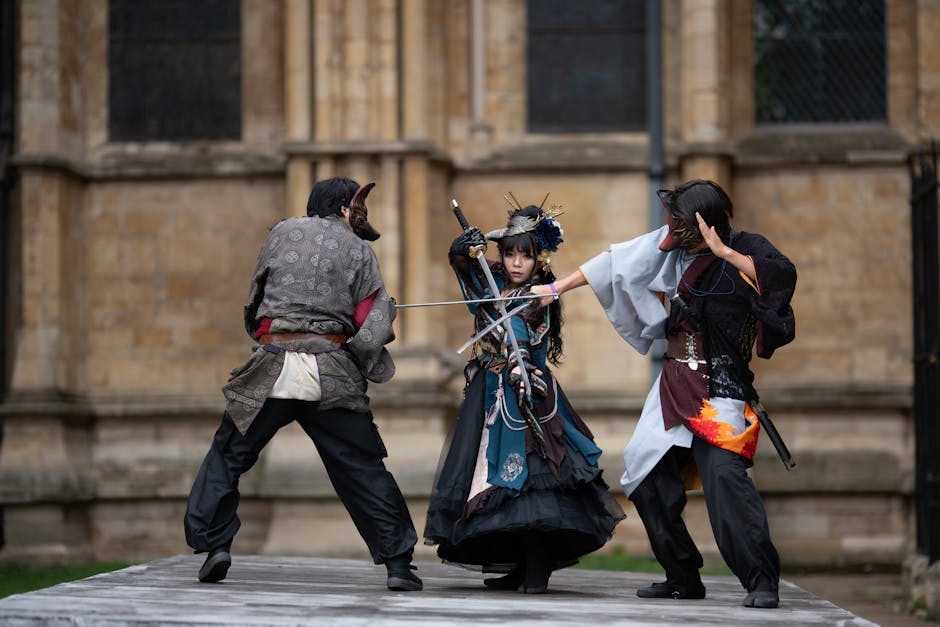 Three adults in intricate cosplay costumes perform sword fight outdoors.